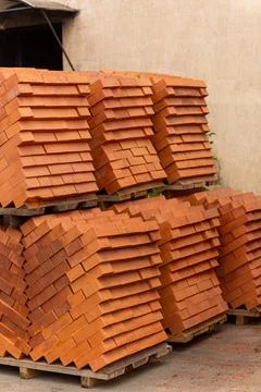 Stacks of new, red ceramic brick stacked on wooden pallets. Fotos Stock