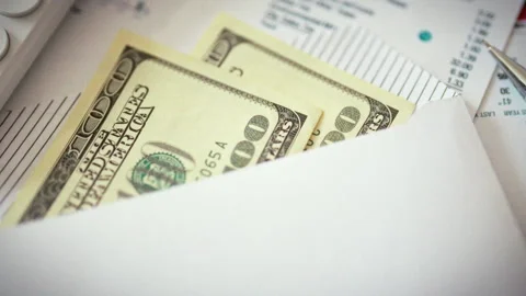 Stacks of one hundred dollar bills protrude from envelope surrounded by busi Stock Footage 346393245