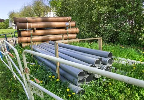 Stacks of orange and gray plastic pipes at a construction site in France. 库存照片