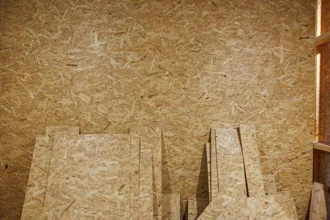 Stacks of OSB panels lean against OSB wall in workshop setting Stock Photos