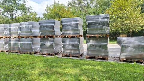 Stacks of palletized goods wrapped in plastic outdoors Stock Photos