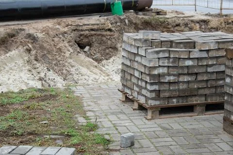 Stacks of paving bricks on pallets at road construction site Stock Photos