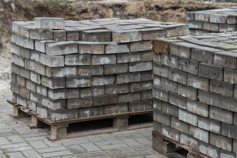 Stacks of paving bricks on pallets at road construction site Stock Photos