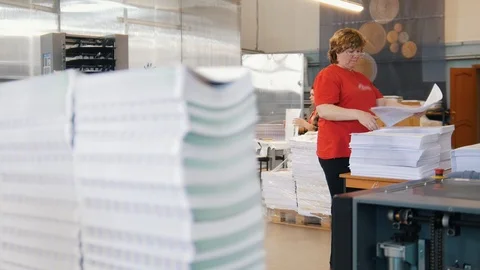 Stacks of printed edition in front of working woman sort the newspapers in the Stock Footage 89624321