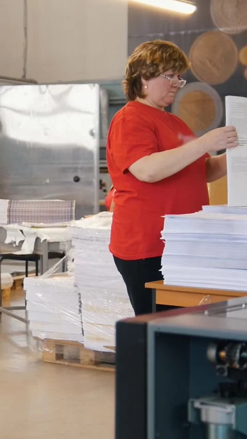 Stacks of printed edition in front of working woman sort the newspapers in the Stock Footage 346706637