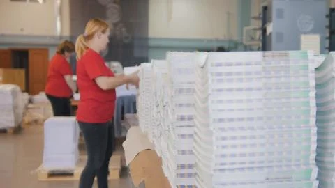 Stacks of printed edition in front of working woman sort the newspapers in the Stock Photos