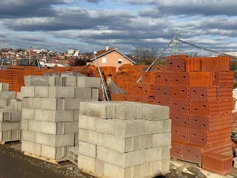 Stacks of red bricks and concrete blocks at construction supply yard. Build.. Stockfoto's