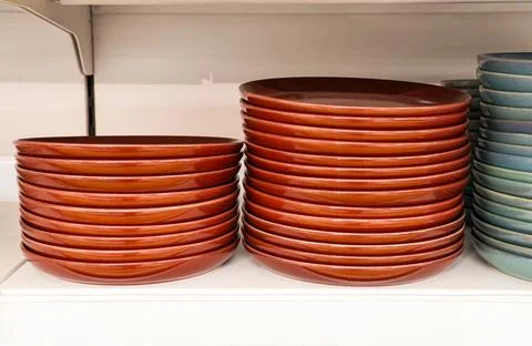Stacks of red ceramic plates and blue ceramic plates on a store shelf displ.. Stock Photos