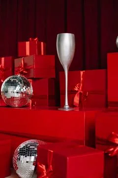 Stacks of red gift boxes and disco balls in front of a red curtain. Stock Photos