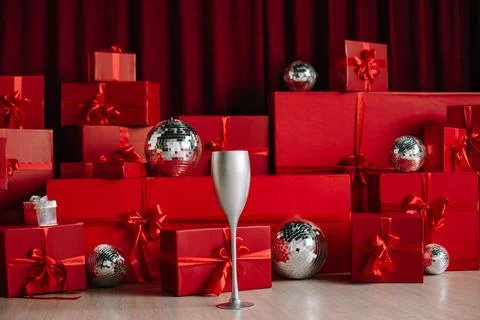 Stacks of red gift boxes and disco balls in front of a red curtain. Stock Photos