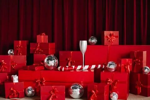 Stacks of red gift boxes and disco balls in front of a red curtain. Stock Photos