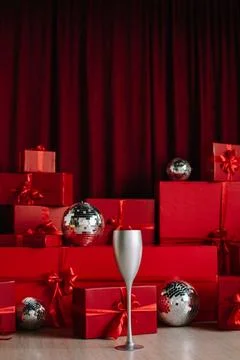 Stacks of red gift boxes and disco balls in front of a red curtain. Stock Photos