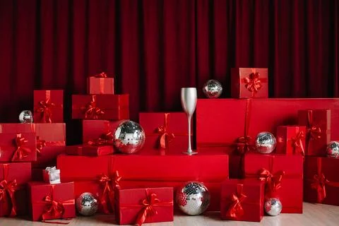 Stacks of red gift boxes and disco balls in front of a red curtain. Stock Photos
