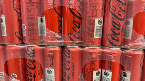 Stacks of red soda cans wrapped in plastic packaging in a store display Stock Footage 338324570