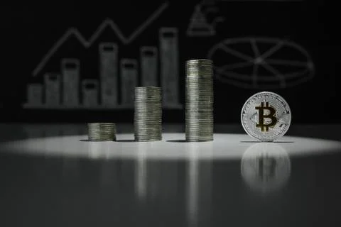 Stacks of silver bitcoins against the background of charts of crypto-currencies Stock Photos