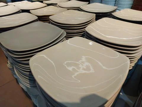 Stacks of Square Ceramic Plates with Embossed Floral Pattern in Neutral Tones Stock Photos