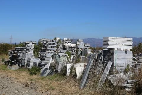 Stacks of stone blocks and slabs stored outdoors in a rural landscape Stock Photos