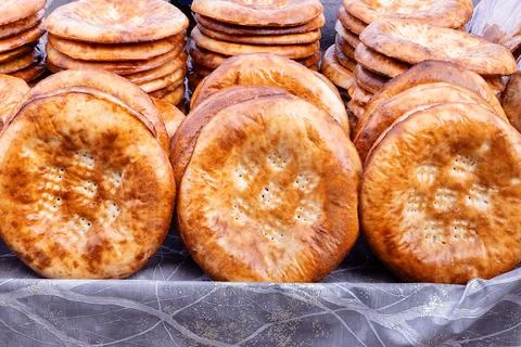 Stacks of traditional Uzbek flatbread displayed at a bazaar in Bukhara. Gol.. Stock Photos