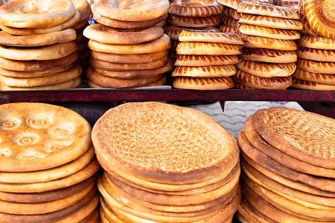 Stacks of traditional Uzbek flatbread displayed at a bazaar in Bukhara. Gol.. Stock Photos