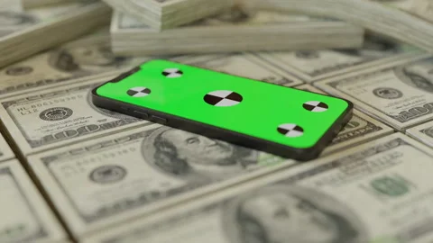 Stacks upon stacks of one hundred dollars and a phone with green screen on it Stock Footage 253600321