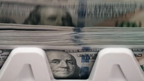 Stacks of U.S. currency being processed in a money counting machine, showcasing Stock Footage 333979080