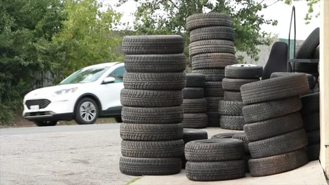Stacks of used tires on top of each other on cement concrete pavement in front Stock Footage 249103306