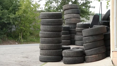 Stacks of used tires on top of each other on cement concrete pavement in front Stock Footage 249103307