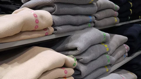Stacks of warm sweaters of different sizes and colors on the table. Stock Footage 296339344