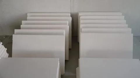 Stacks of white plasterboard panels on concrete floor during renovation Stock Footage 334448577