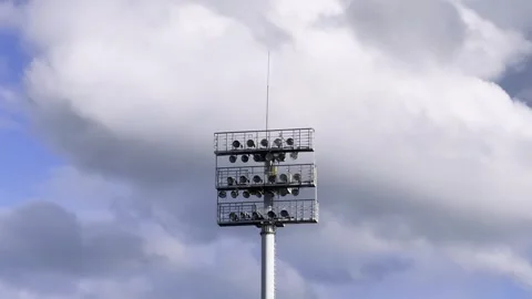 Stadium floodlight mast with multiple lamps and metal platforms against large Stock Footage 340139066