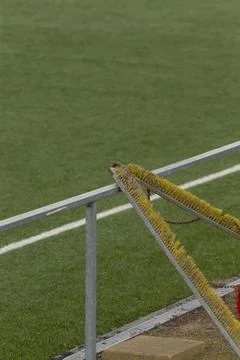 Stadium railing and turf brush beside green artificial field Stock Photos