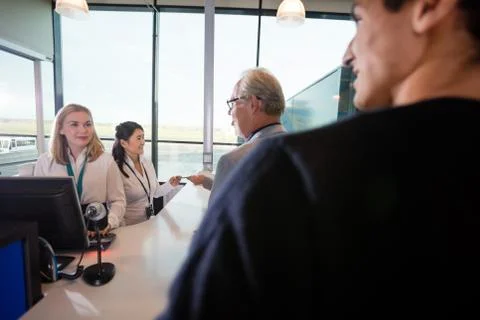 Staff And Passengers At Checking Counter In Airport Stock Photos