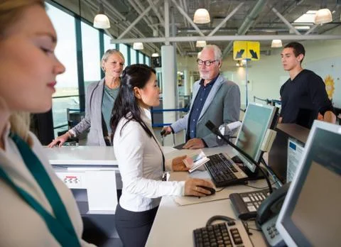 Staff Checking Passport On Computer While Passengers Waiting In Stock Photos