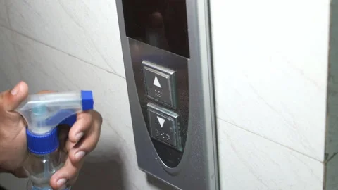 Staff hand using wet wipe cleaning an elevator push button control panel Stock Footage 132229299