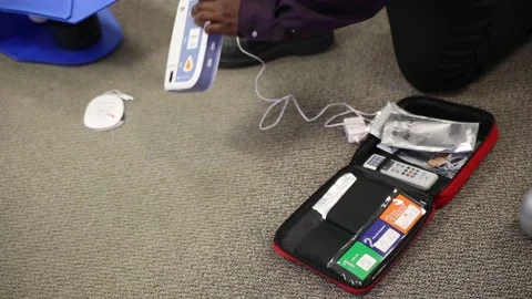 Staff practicing first aid cpr with AED machine and dummy dolls Stock Footage 202275346
