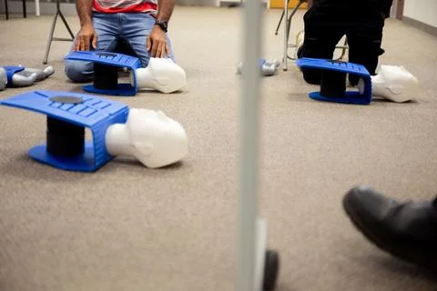 Staff practicing first aid cpr with their fingers and AED machine Stock Photos