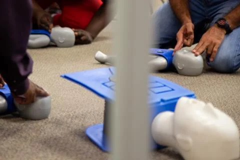 Staff practicing first aid cpr with their fingers and AED machine Stock Photos
