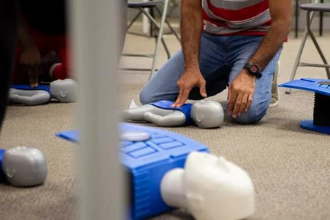 Staff practicing first aid cpr with their fingers and AED machine Stockfoto's