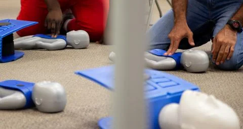 Staff practicing first aid cpr with their fingers and AED machine Stock Photos