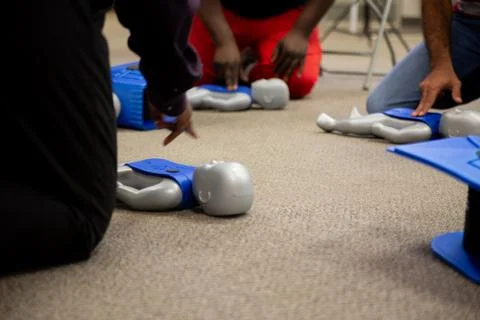 Staff practicing first aid cpr with their fingers and AED machine Stock Photos