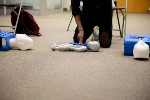 Staff practicing first aid cpr with their fingers and AED machine Stock Photos