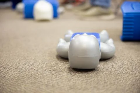 Staff practicing first aid cpr with their fingers and AED machine Stock Photos