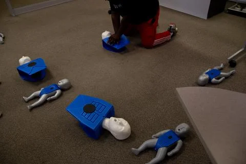 Staff practicing first aid cpr with their fingers and AED machine Stock Photos