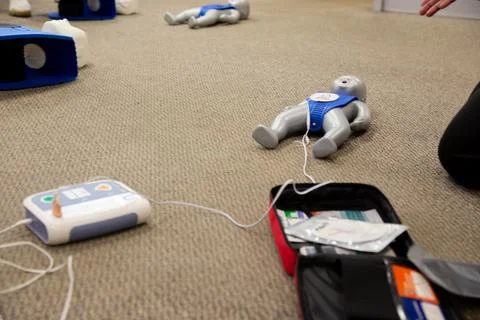Staff practicing first aid cpr with their fingers and AED machine Stock Photos