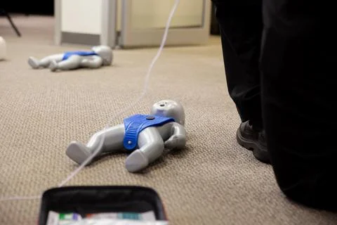 Staff practicing first aid cpr with their fingers and AED machine Stock Photos
