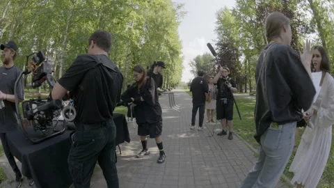 Staff prepares camera equipment setup on peaceful park alley Stockbeeldmateriaal 308934531