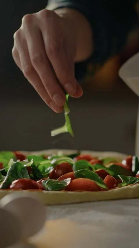 Staff preparing delicious pizza by adding fresh basil to mozzarella and vegg Stock Footage 331726097