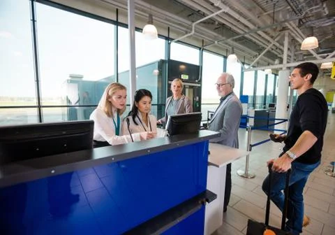 Staff Using Computer While Passengers Waiting In Airport 写真素材