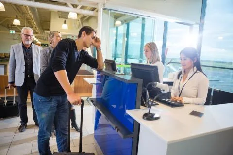 Staff Using Computers While Passengers Waiting At Airport 写真素材