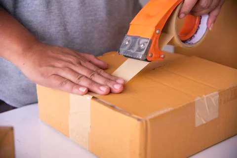 The staff is using the tape to pack the package goods to the customer. Stock Photos
